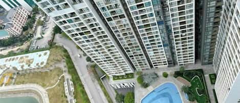 Un immeuble résidentiel de grande hauteur doté de nombreux balcons, d’une piscine et d’un espace paysager.