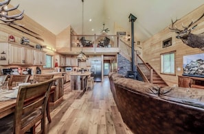A spacious interior with a high ceiling, a central island in the kitchen, and a staircase leading to an upper level.