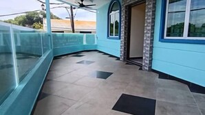 A corridor with a tiled floor, a glass railing on one side, and a door leading to a room. - Sunstar Hotel (Batu Maung)