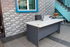 Un comptoir d’accueil avec un ordinateur, une chaise et une petite table sur laquelle se trouvent divers objets.