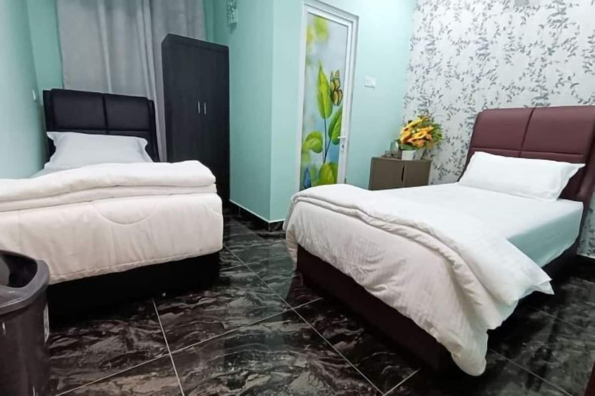 A room with two beds, a wardrobe, a cabinet, and a door with a floral design.