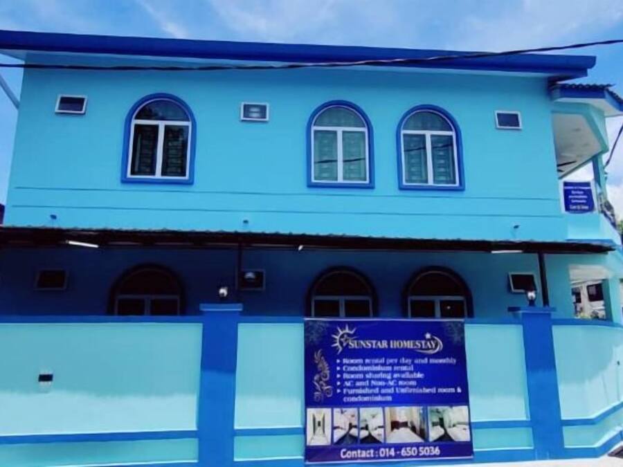 Un edificio de dos plantas con fachada azul y varias ventanas.