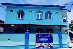 Un edificio de dos plantas con fachada azul y varias ventanas.