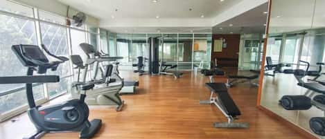 A gym with cardio equipment, weight machines, and a mirror wall.