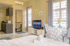A hotel room with a bed, a TV, a dining table with chairs, a kitchenette, and a bathroom. - MayTower by Horizon Homes (Kuala Lumpur)