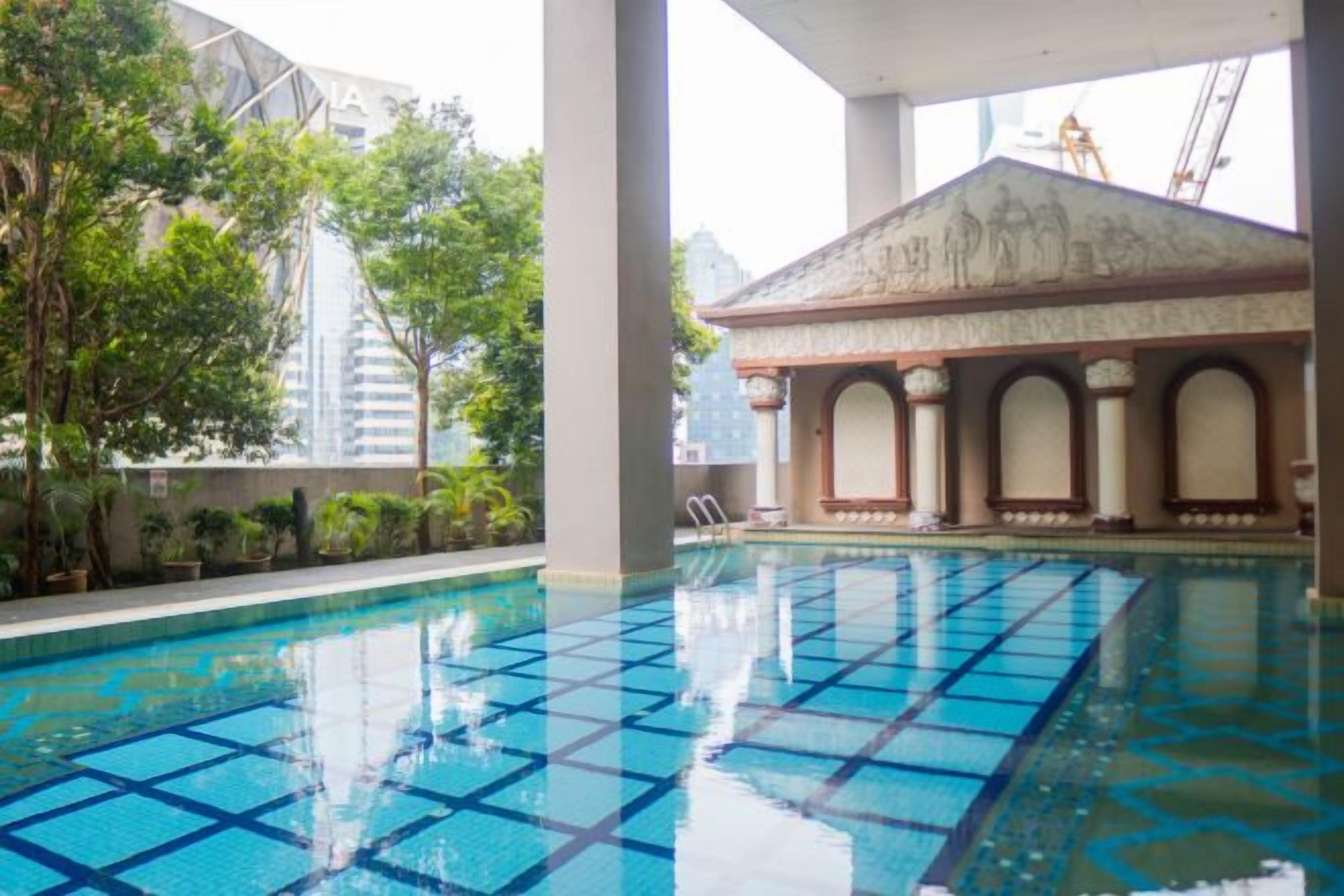 An indoor swimming pool with a tiled floor, surrounded by columns and a building with a dome structure.