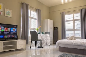 A hotel room with a bed, a desk with a chair, a television, and a wardrobe. - MayTower by Horizon Homes (Kuala Lumpur)