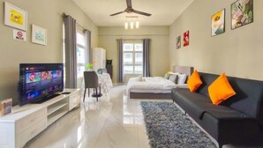 A modern hotel room with a flat-screen TV, a bed, a black sofa, and a ceiling fan. - MayTower by Horizon Homes (Kuala Lumpur)