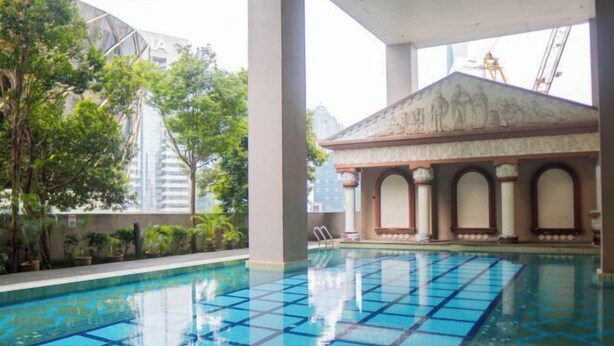 An indoor swimming pool with clear blue tiles, surrounded by greenery and a classical building with columns. - MayTower by Horizon Homes (Kuala Lumpur)