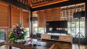 Una sala de estar moderna con un mueble bajo de televisión de madera, un televisor de pantalla plana y un ventanal grande con contraventanas de madera.