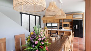 Una cocina moderna con armarios de madera, una mesa de comedor con sillas y un ventanal grande.