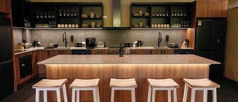 A modern kitchen with a central island, bar stools, and a variety of kitchenware.