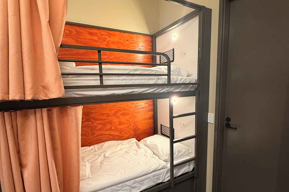 A bunk bed with a wooden headboard, a curtain, and a door.