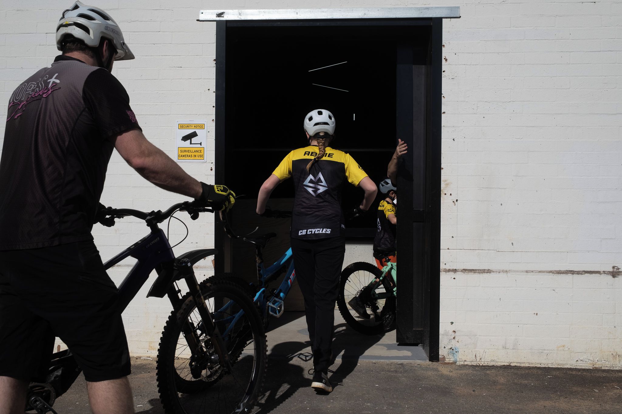 A person with a bicycle entering a building through a door.