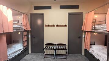 Un dormitorio con literas, un escritorio central y un tragaluz.