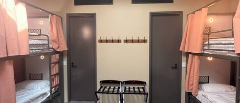 A dormitory room with bunk beds, a central desk, and a skylight.