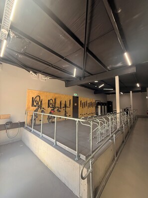 Un espace intérieur propre et bien éclairé, doté de rampes en métal, d'un mur en bois avec des supports à vélos et d'un sol en béton.