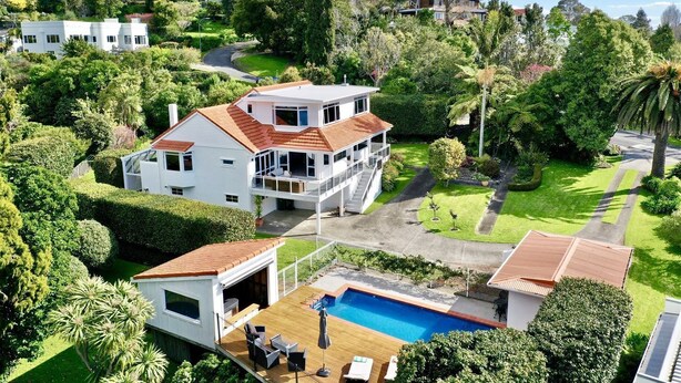 Een tweelaags huis met een ruim terras, een zwembad en een keurig onderhouden tuin.