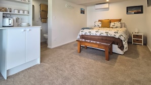 Een slaapkamer met een bed, nachtkastjes, een kledingkast en een kleine kitchenette.
