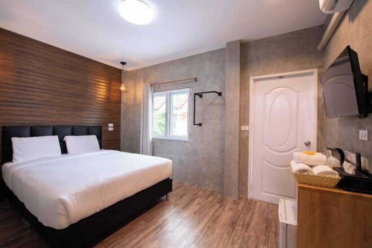 Une chambre à coucher avec un lit, une télévision, une porte et une fenêtre.