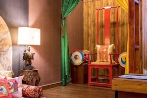A room with a wooden wall, a red chair with colorful cushions, a lamp, and a table with a book. - Fahrenheit88 - Kuala Lumpur Bukit Bintang Korea Theme (Kuala Lumpur)
