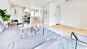 Ein modernes Wohnzimmer mit einer Couch, einem Couchtisch und einem Essbereich mit St ühlen.