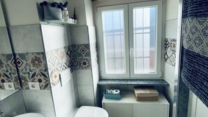 Ein Badezimmer mit Toilette, Waschbecken und einem Fenster über dem Waschbecken.