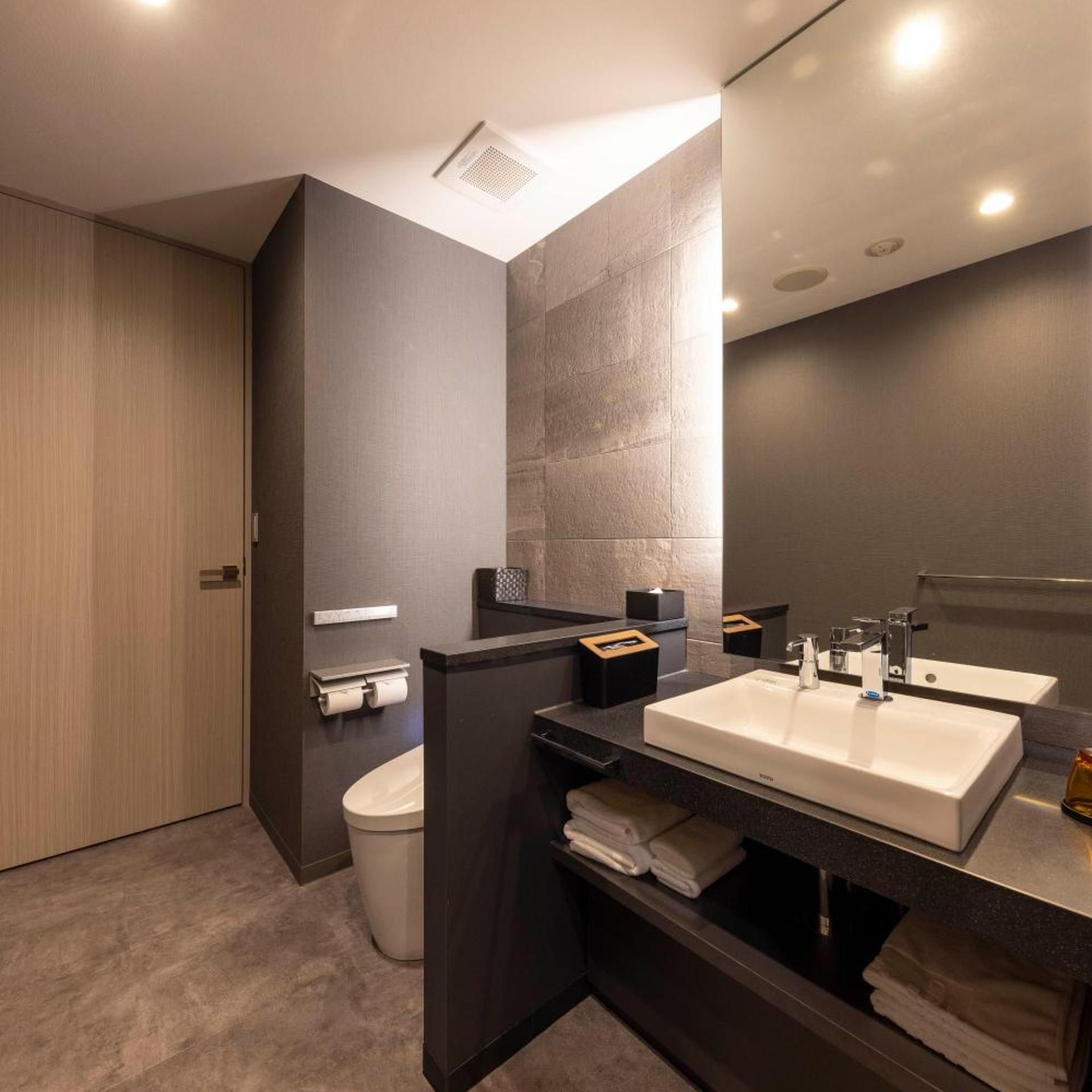 Un baño moderno con un espejo grande, dos lavabos y un inodoro.