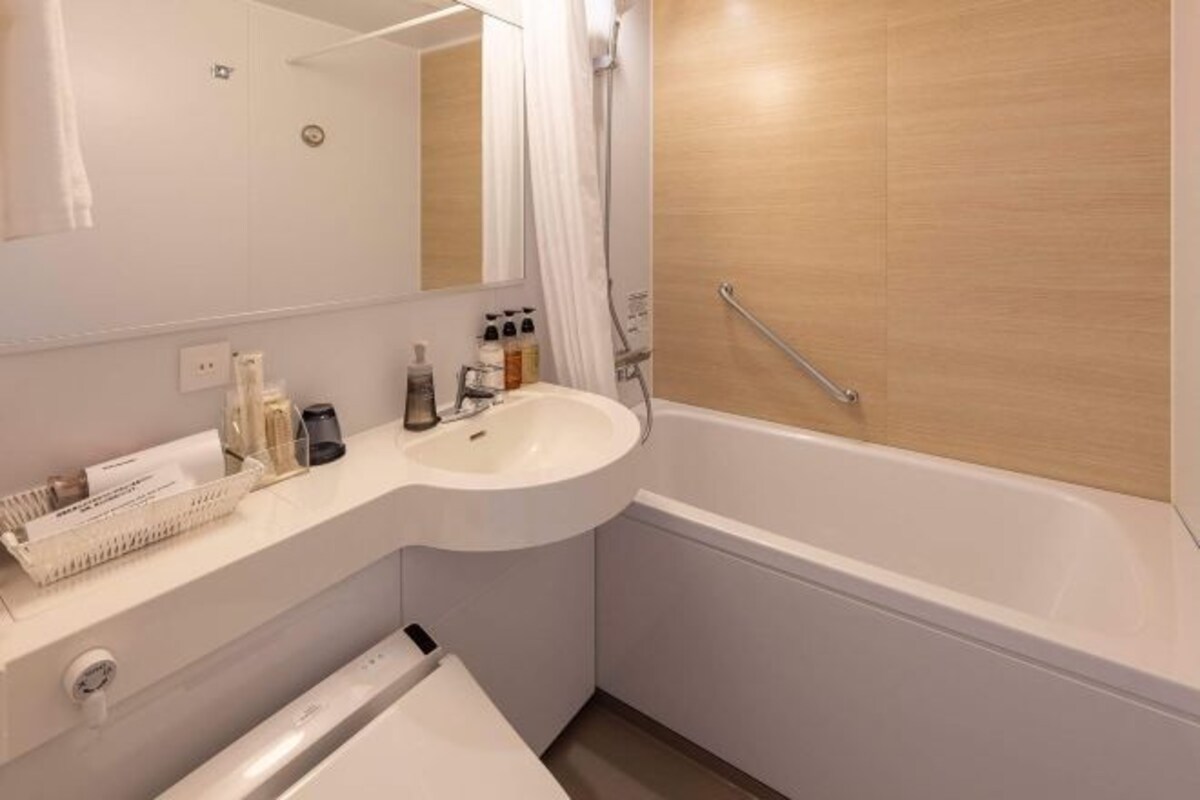 Ein modernes Badezimmer mit einem weißen Waschbecken, einem Spiegel und einer Dusche.