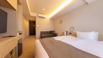 A hotel room with a bed, bedside table, lamp, and a television on a stand.