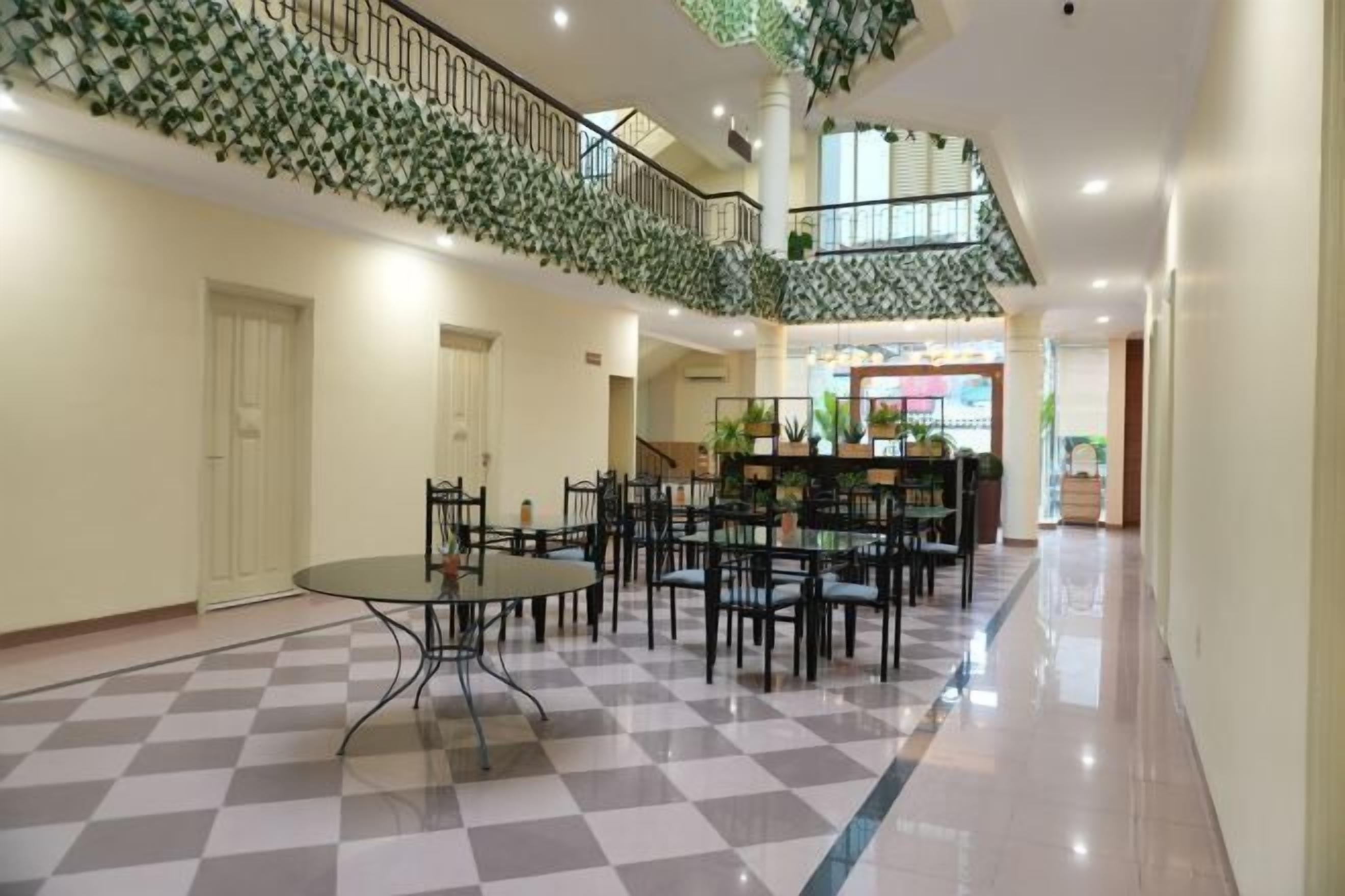 A spacious lobby with a checkered floor, multiple seating areas, and a staircase connecting two levels.