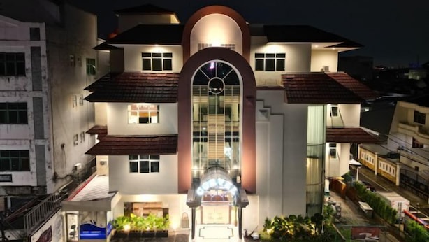 Ein modernes Hotel mit einem zentralen Bogenportal, mehreren Balkonen und einer gut beleuchteten Fassade.