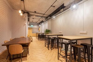 A conference room with a long table, several chairs, and a bar area with stools. - Bluewaters Female-Only Hostel (Singapore)