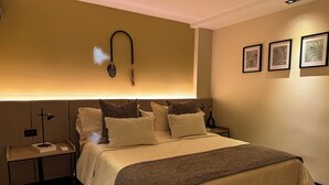 Quarto moderno com cama grande, mesa de cabeceira com luminária e luminária na parede.