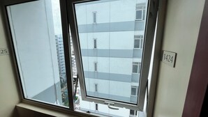 Une fenêtre donnant sur un immeuble doté de nombreuses fenêtres et de balcons.