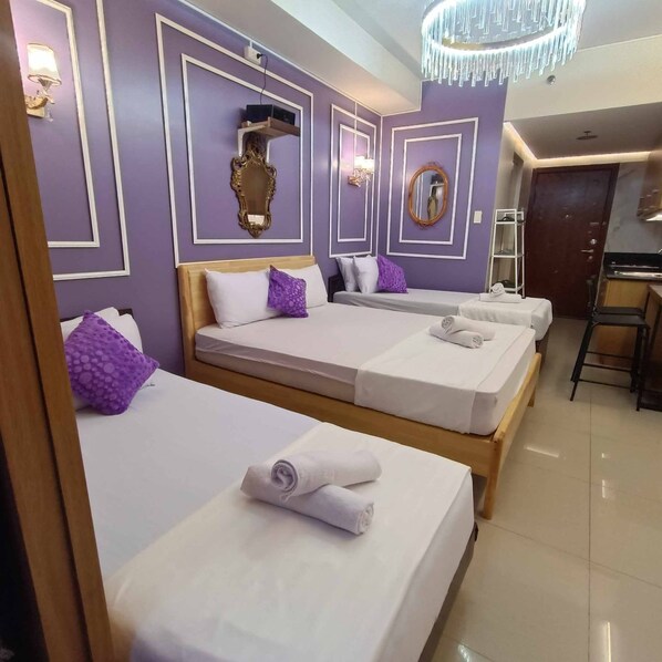 A hotel room with two beds, a small desk, and a bathroom. - Royal Purple Cinema Room (Pasay)