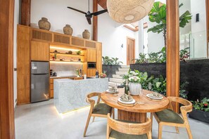 A modern kitchen with wooden cabinets, a built-in fridge, and a dining area with a round table and chairs.