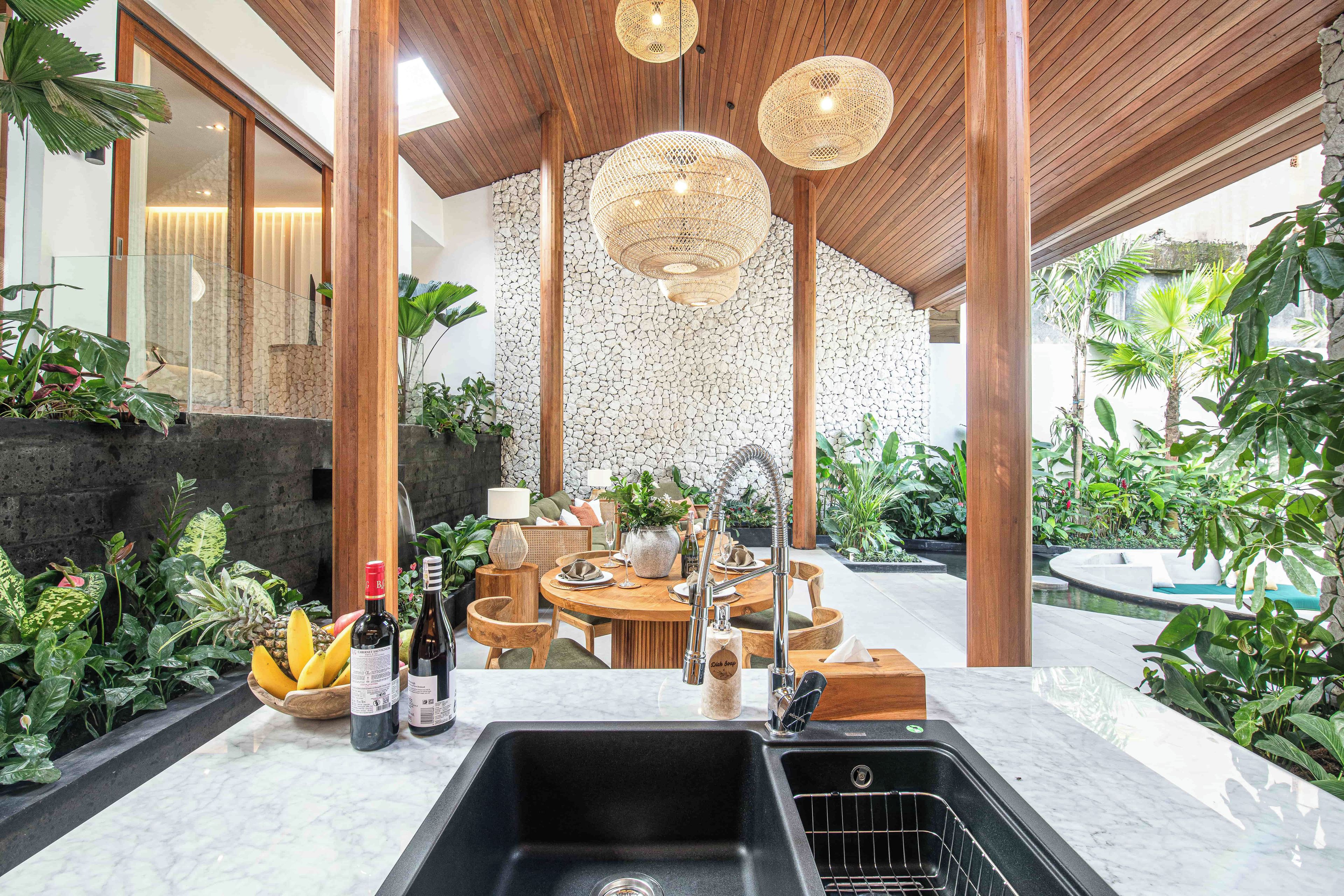 A modern kitchen with a stone backsplash, wooden ceiling, and a dining area with a round table and chairs.