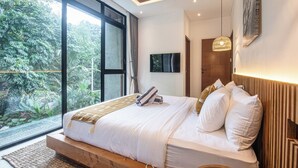 A modern bedroom with a large window, a bed with white bedding, a wooden headboard, and a hanging light fixture. - Designer 5br Villa, 400m to Café Del Mar (Seminyak)