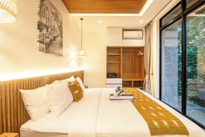 A modern bedroom with a large bed, a wooden headboard, a bedside table, a nightstand, a wall-mounted air conditioner, a wardrobe, and a large window with a view of greenery. - Stylish 5BR Designer Villa, 400m to the Ocean (Seminyak)