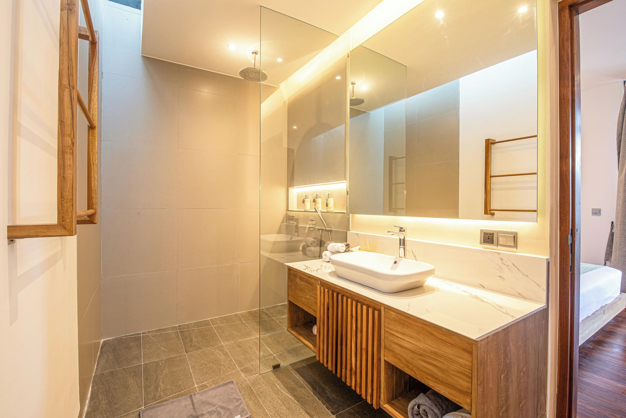 A modern bathroom with a large mirror, a wooden vanity, and a shower area.