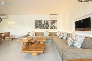 A modern living room with a sofa set, wooden coffee table, and wall-mounted artwork. - Luxury 6-bedroom Villa in Canggu, Walk to the Beac (Seminyak)