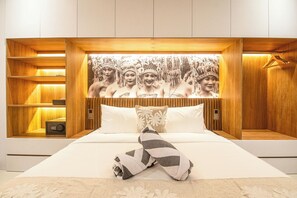 A modern bedroom with a large bed, wooden headboard, and a wall-mounted artwork. - Elegant 5BR Modern Villa Steps From Café Del Mar (Seminyak)