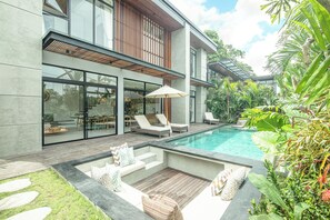 Une maison moderne dotée d’une piscine, d’un espace salon extérieur et d’une végétation luxuriante.