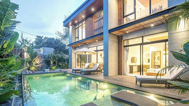 A modern house with a swimming pool, lounge chairs, and a well-lit outdoor area. - Chic 5BR Canggu Villa 400m to Café Del Mar (Seminyak)