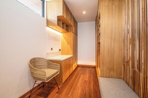 A narrow hallway with wooden flooring, a wicker chair, a white countertop, and a wooden wardrobe. - Tropical Luxury 6BR Canggu Escape Near the Ocean (Seminyak)