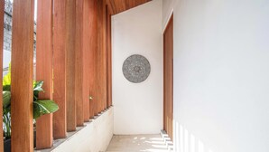 Um corredor estreito com ripas de madeira de um lado e uma parede branca do outro. Um prato decorativo circular está pendurado na parede.