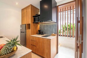 Cozinha moderna com armários de madeira, micro-ondas embutido e geladeira de aço inoxidável.