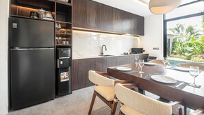 Una cocina moderna con armarios oscuros, un refrigerador empotrado y un comedor con mesa y sillas.