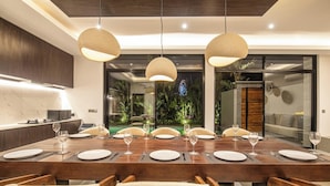 Un comedor moderno con una larga mesa de madera dispuesta para seis personas, rodeada de sillas tapizadas.